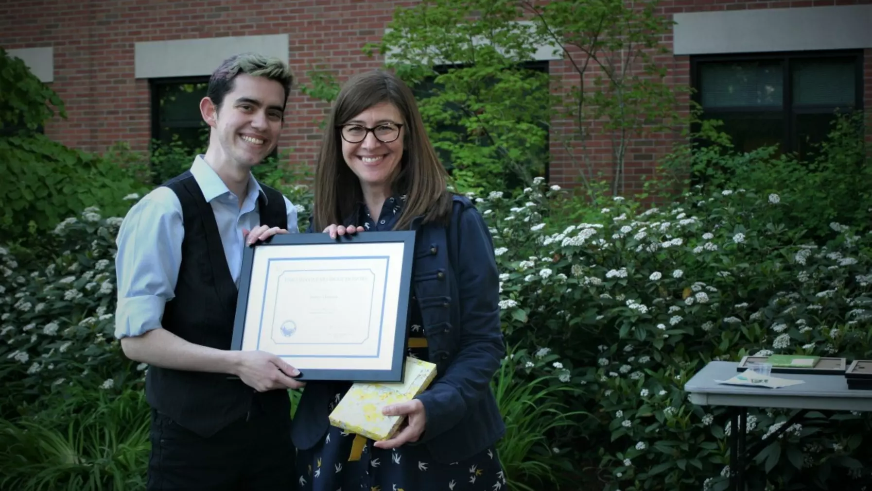 Two people smiling with an award.